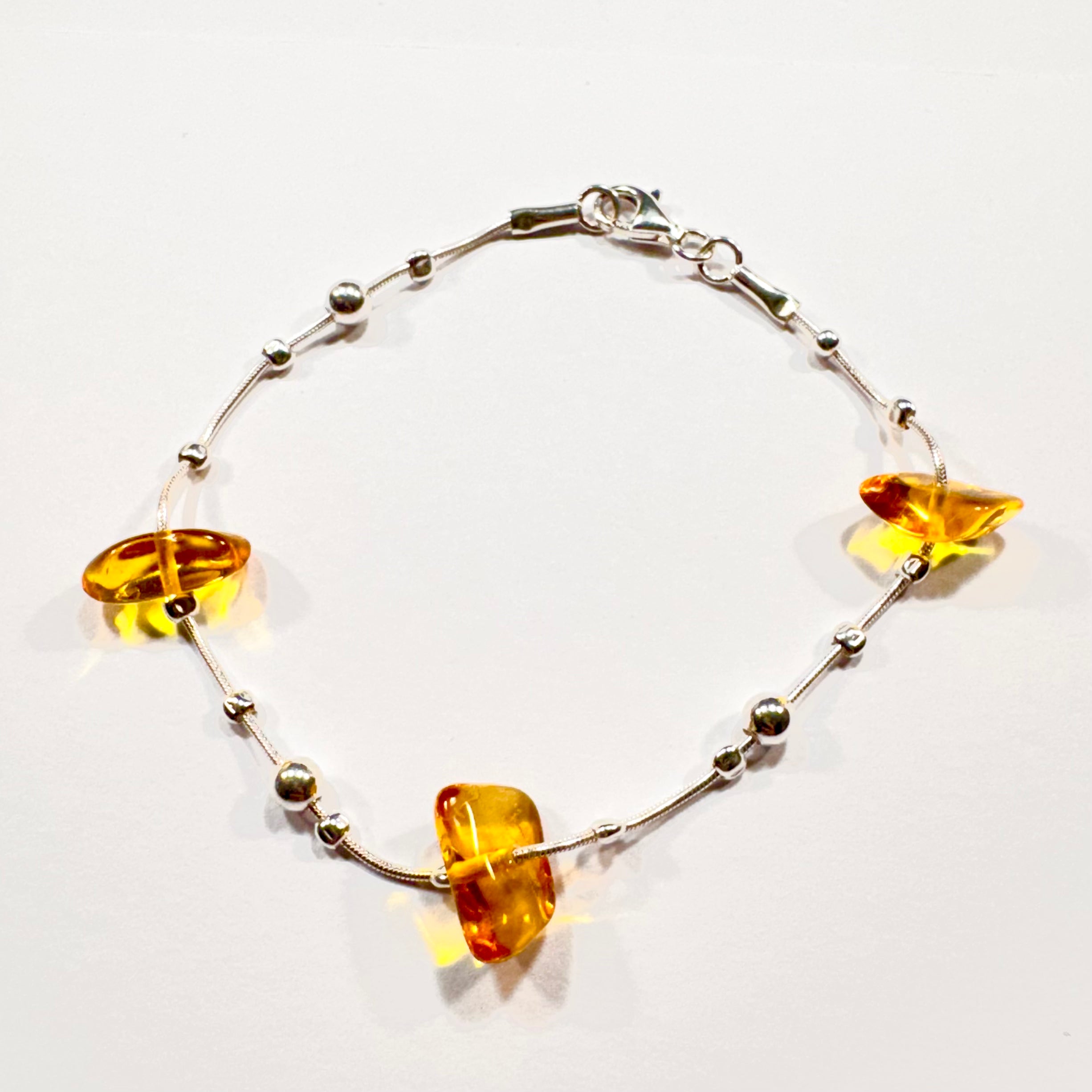 Hochwertiges Bernstein-Armband mit polierten Naturbernsteinen in warmen Farbtönen und edlen Silberdetails – sicherer Verschluss für optimalen Tragekomfort.